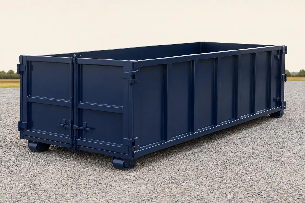 Empty navy open-top roll-off dumpster with a rear swing door, set on a gravel pad